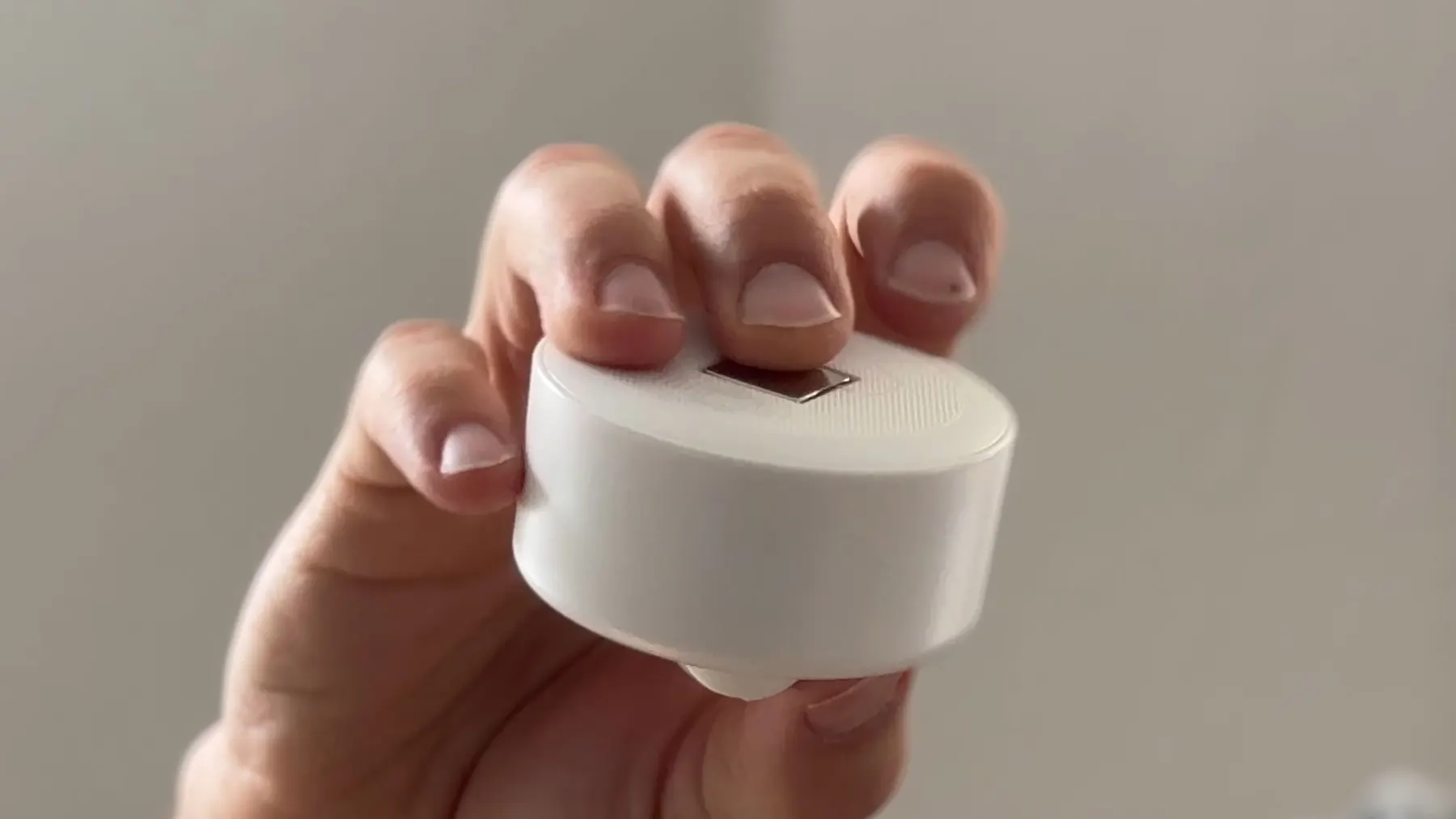 Weisses Sensorgehäuse für thingdust in der Hand – finales Industriedesign